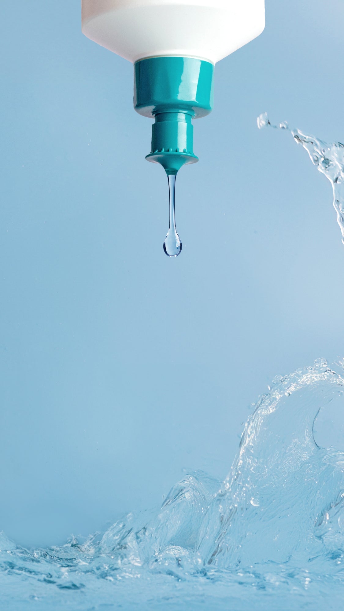 Spülmittel aus einer Flasche tropfend und Wasser in Bewegung