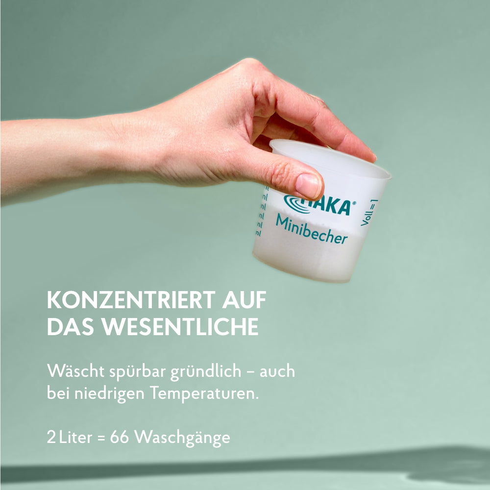 Hand hält HAKA Dosierbecher mit Waschmittel