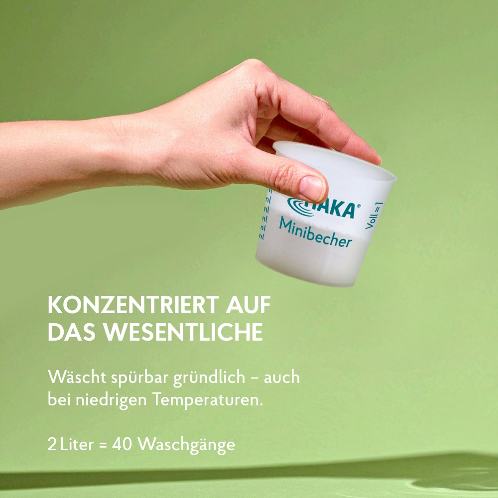 Hand hält Mini Dosierbecher mit wenig Waschmittel